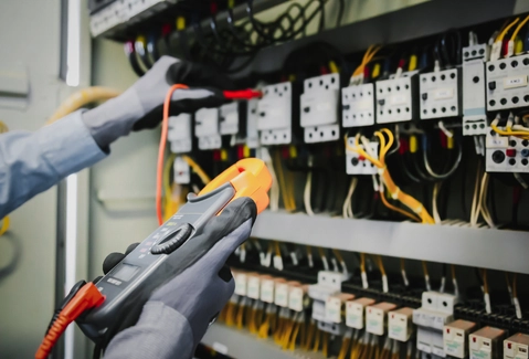 Elektrikář měří multimetrem v rozvaděči při elektroinstalaci
